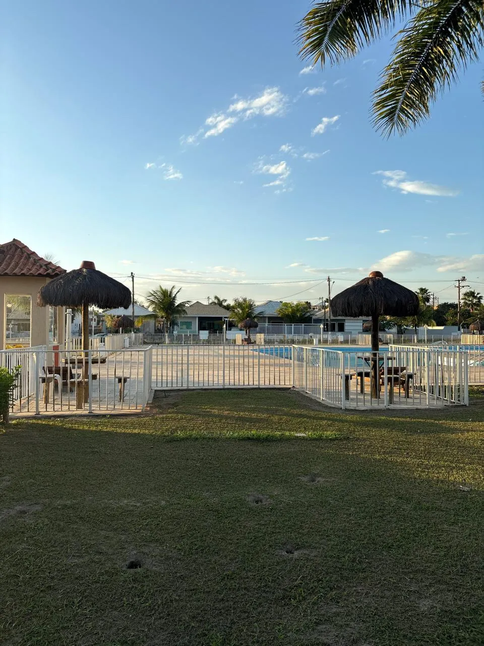 Piscina do condomínio com quiosques de sapê